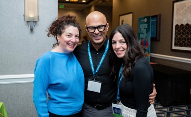 Un grupo de tres padres sonrientes en un evento comunitario