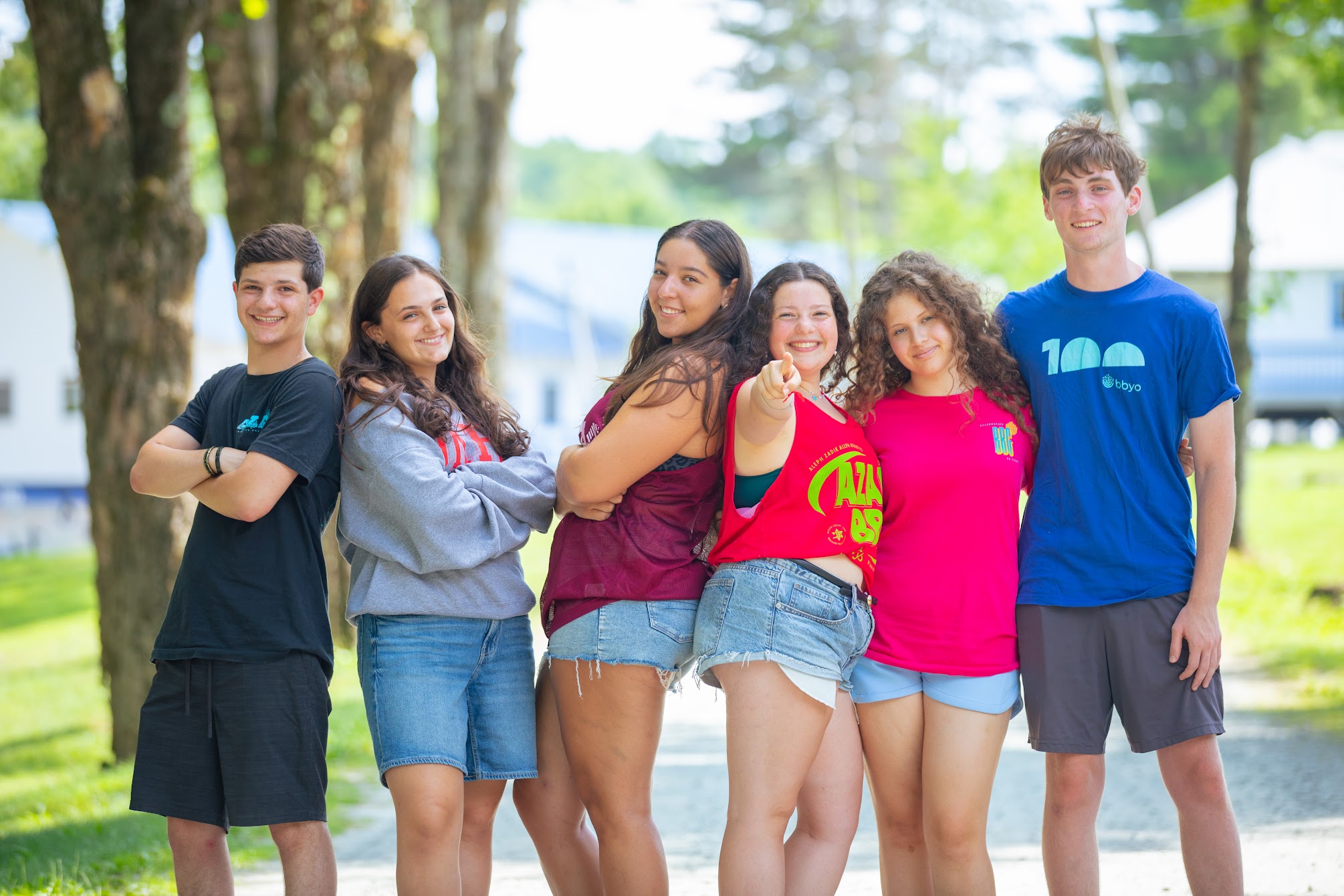 Un grupo variopinto de jóvenes que saltan de alegría en un frondoso jardín durante un evento comunitario.