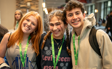 Un grupo de tres padres sonrientes en un evento comunitario